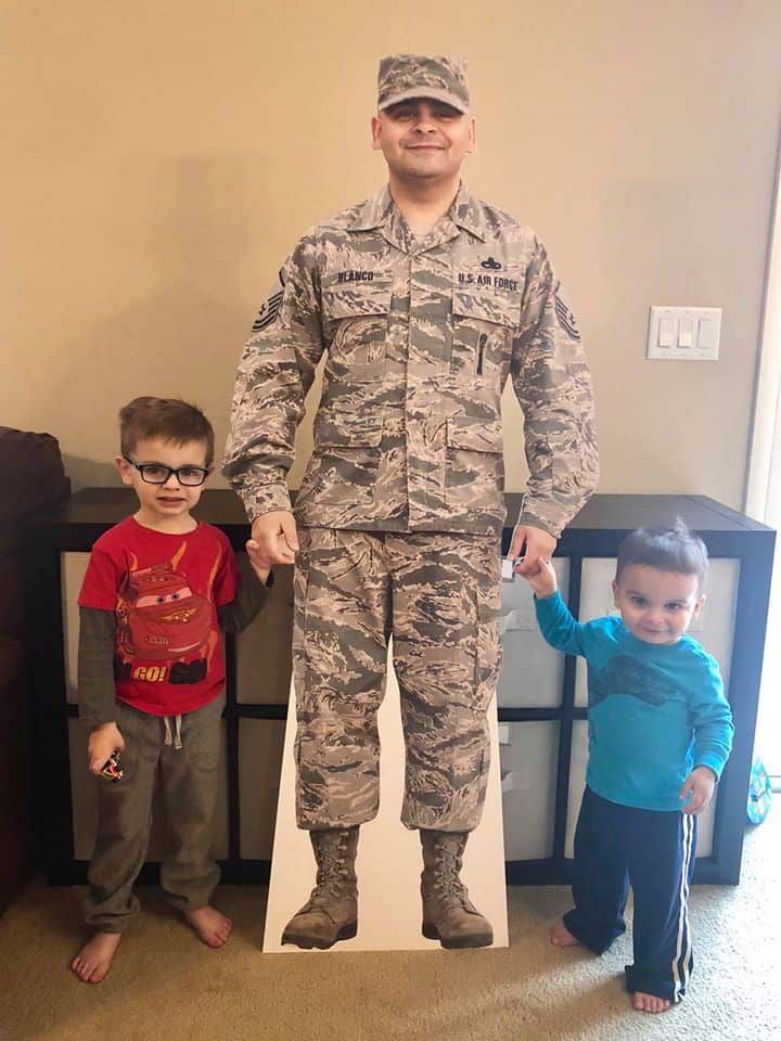 Cardboard standee of a military solider standing with his two young children.