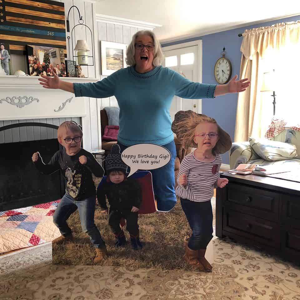 A grandma celebrating with her cardboard cutout grandchildren.