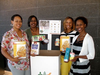 A group of employees posing with donations for the food drive.