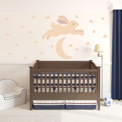 Bunny jumping over moon decal in front of a baby crib.