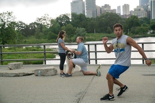 Photobomber runs in front of couple getting engaged on bridge.
