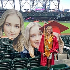 Graduate with loved ones holding cardboard head cutout